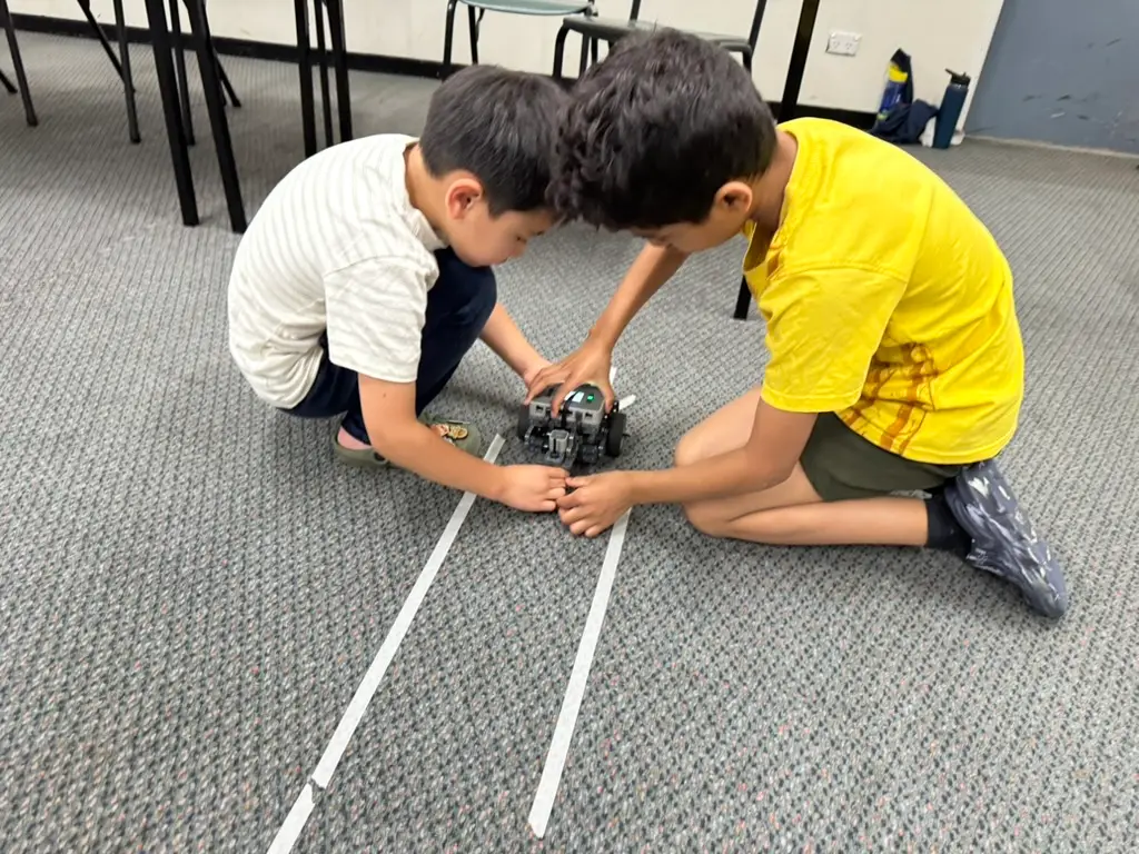 Two students assembling a small robot during a hands-on classroom engineering activity