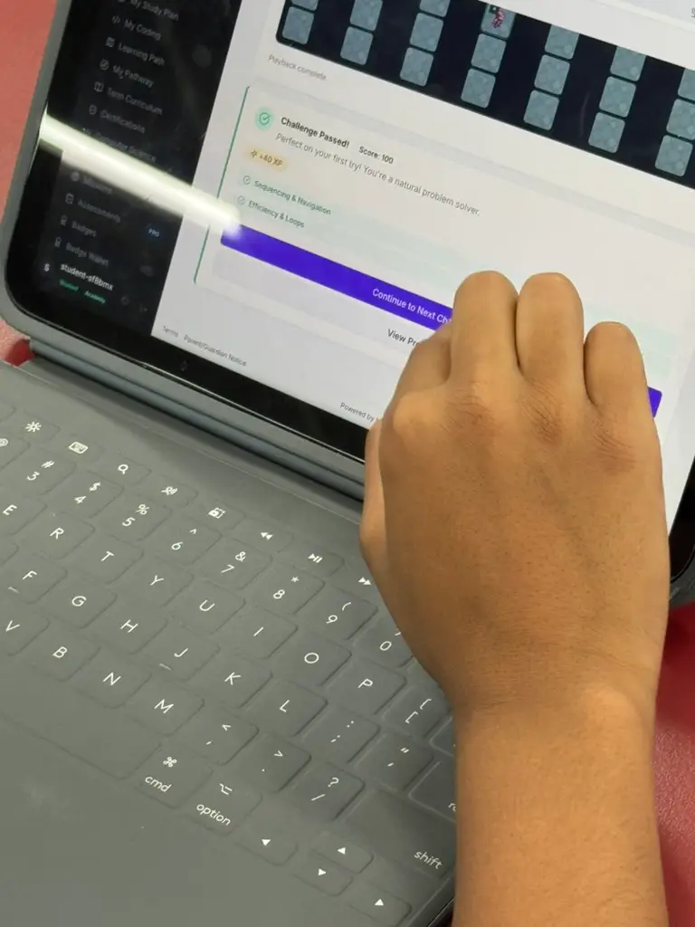 A student using a stylus to complete a guided programming challenge on a laptop